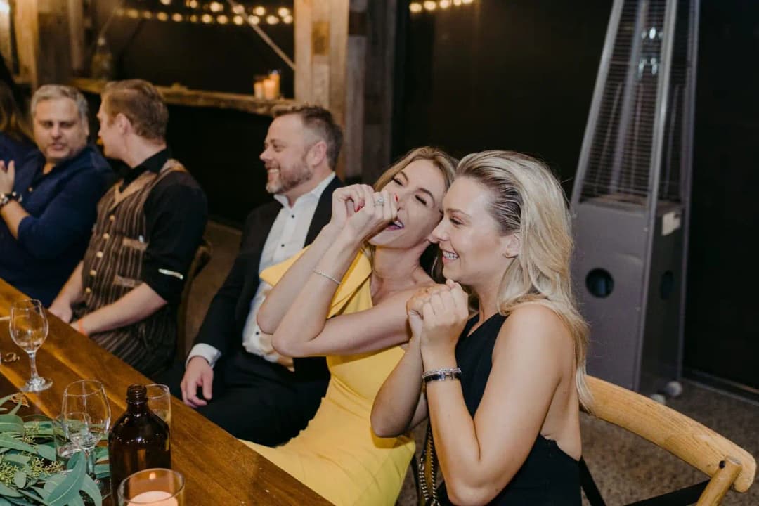 Guests laughing while seated at a long wooden reception table