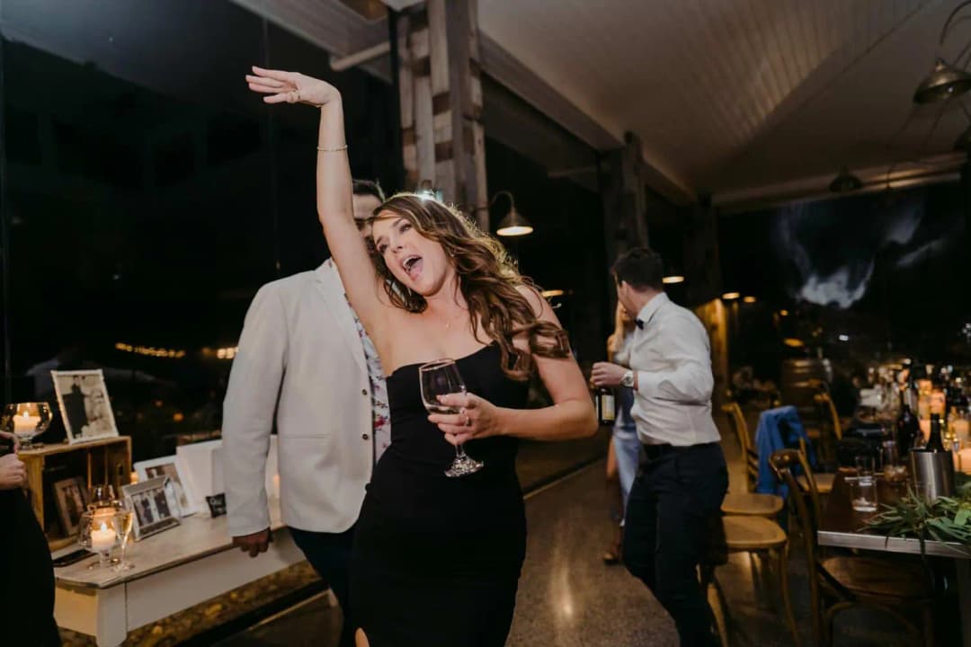 Guest dancing with one arm raised while holding a wine glass
