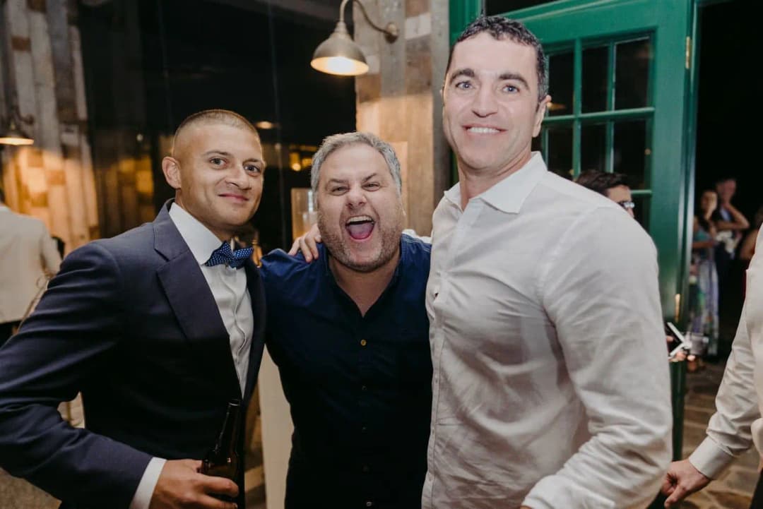 Three smiling men posing together at the reception