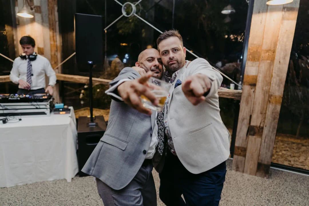 Groom and a guest pointing toward the camera beside the DJ booth