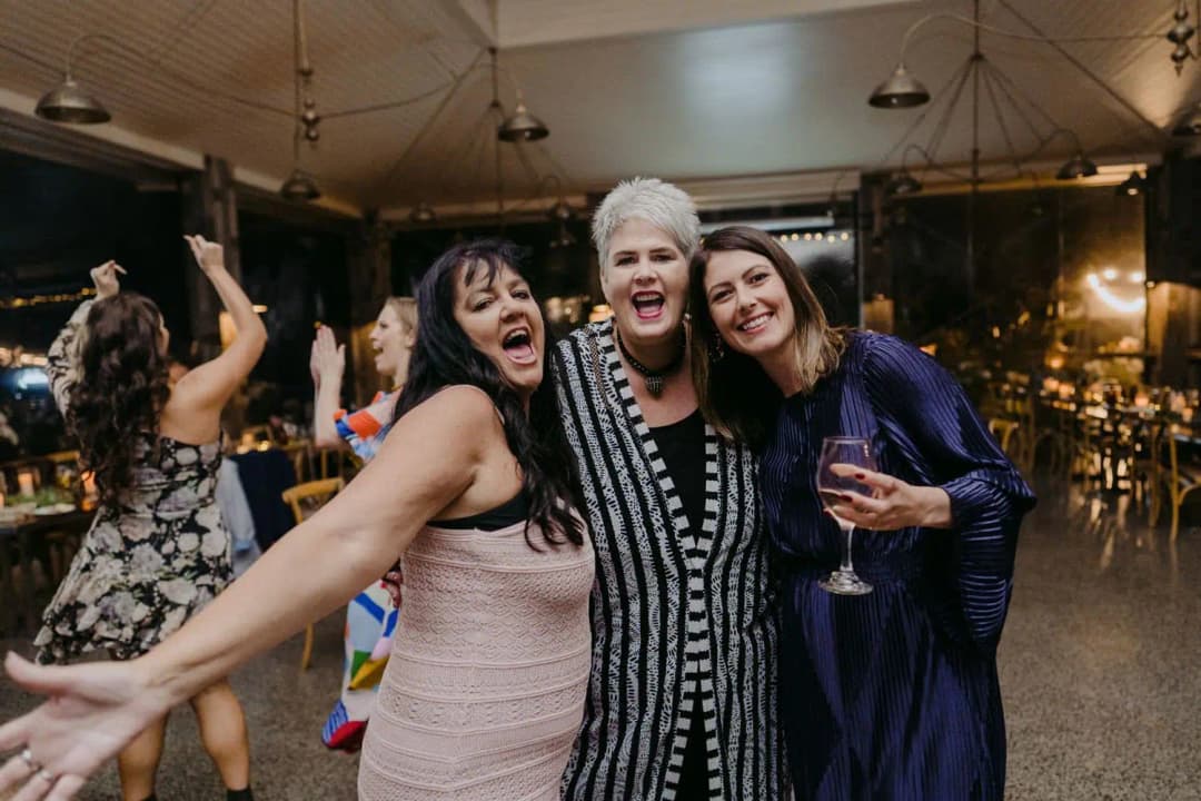 Three women laughing together on the dance floor