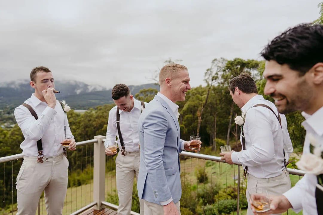 Men laughing together on a balcony overlooking hills