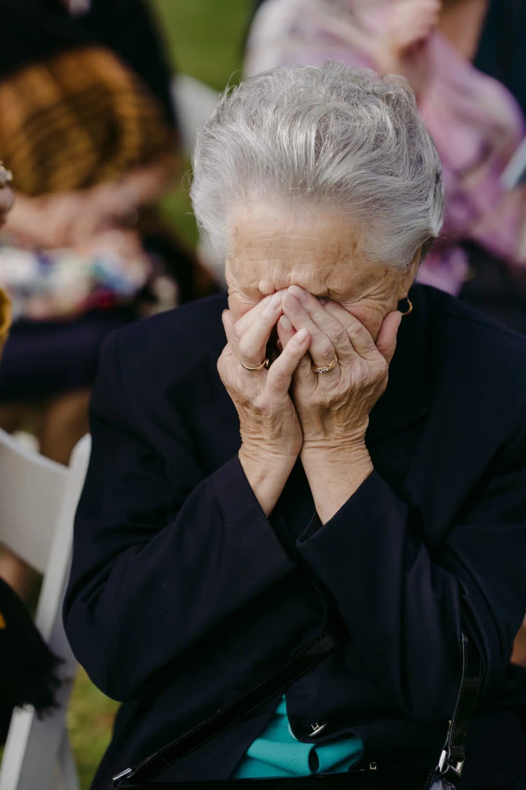 Older guest covers her face with her hands during the wedding.