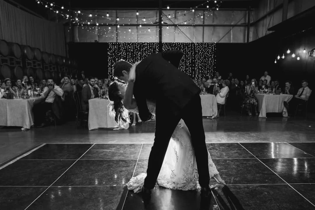 Black and white photograph of the groom dipping the bride during their first dance.