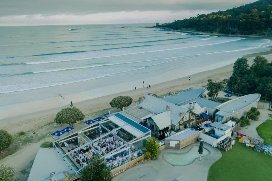 Aerial view of a coastal reception venue beside a sandy beach and ocean.