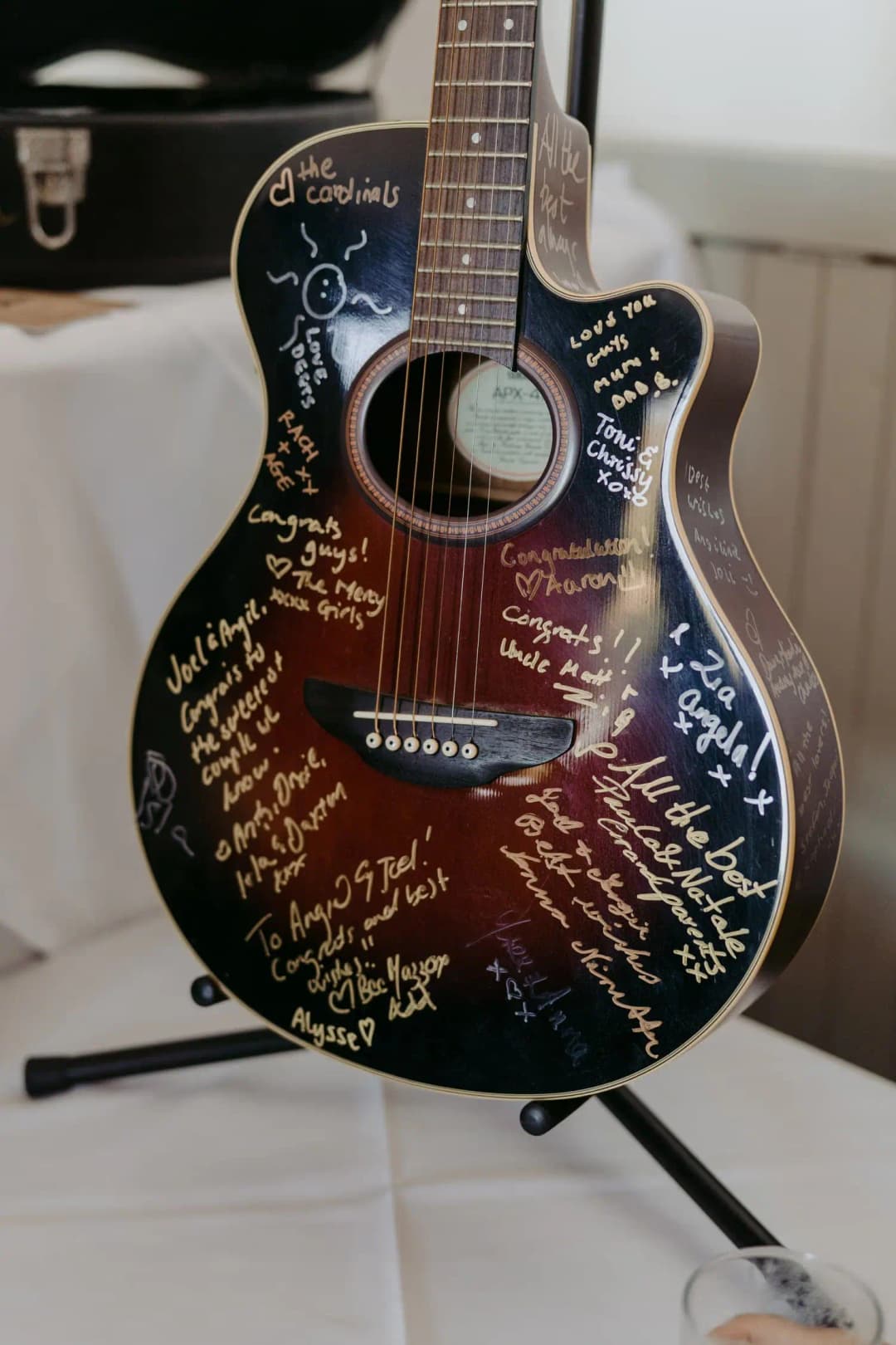 Acoustic guitar covered in handwritten messages rests on a stand.