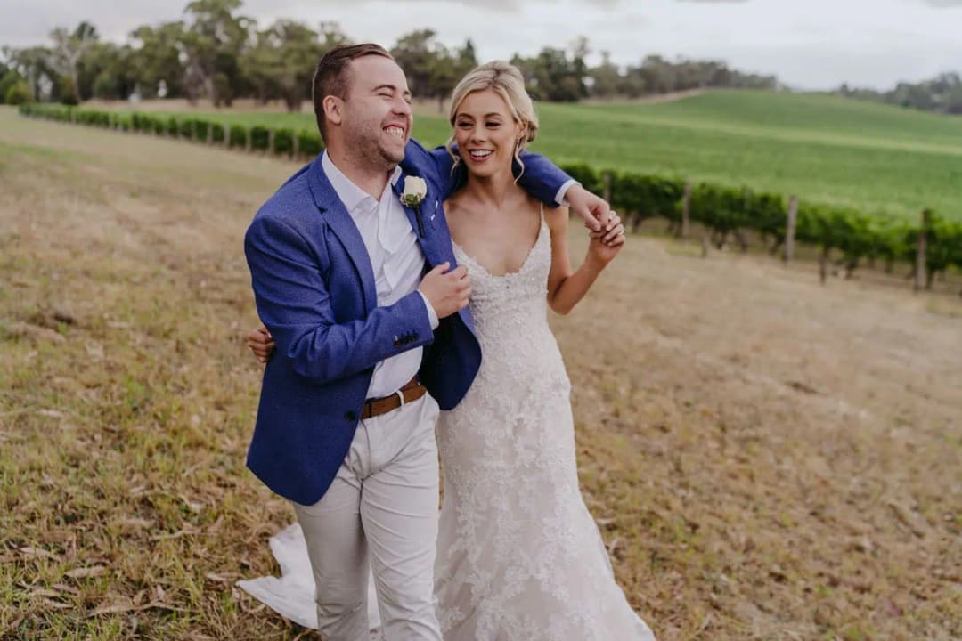 Couple laughs together beside vineyard rows and a harvested field.