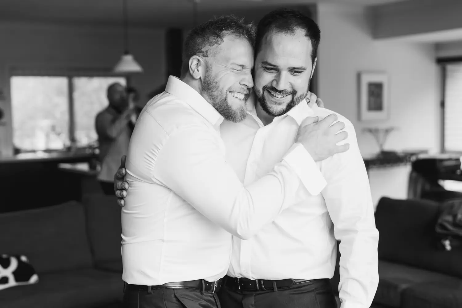 Black and white photograph of two men embracing indoors.