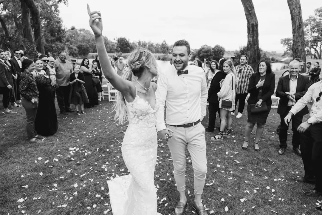 Black and white photograph of newlyweds celebrating as guests throw confetti.