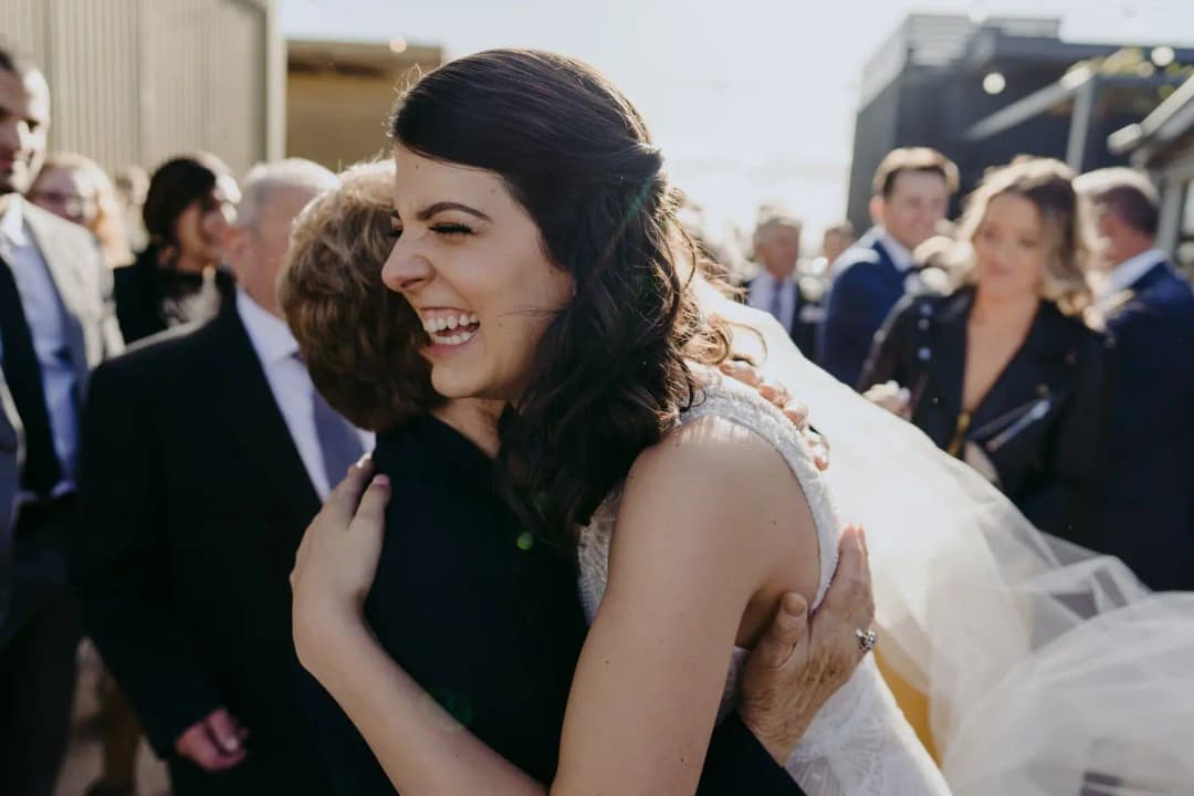 Bride smiles while embracing a guest after the ceremony.