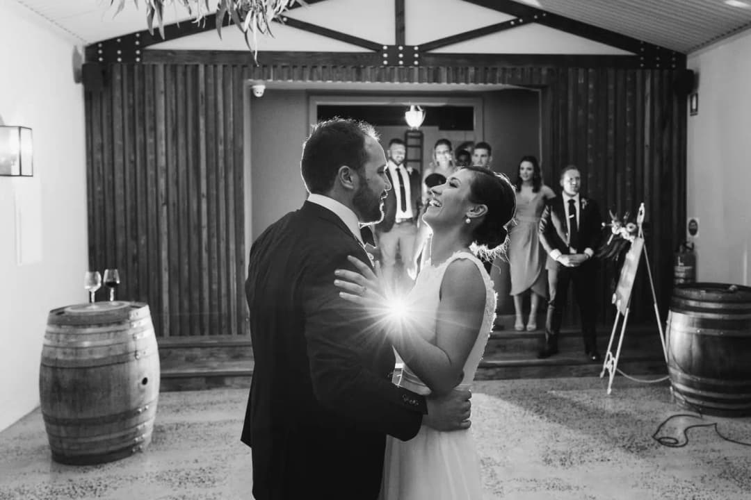 Black and white photograph of the couple laughing during their first dance.