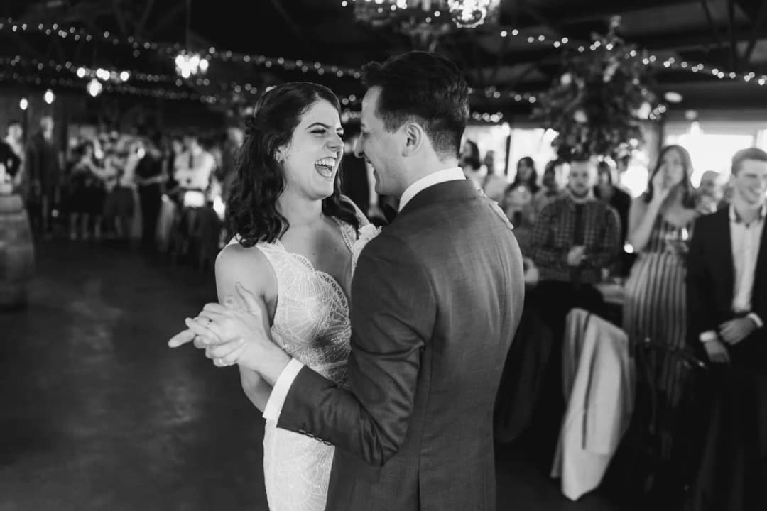 Black and white photograph of the couple smiling at each other while dancing.