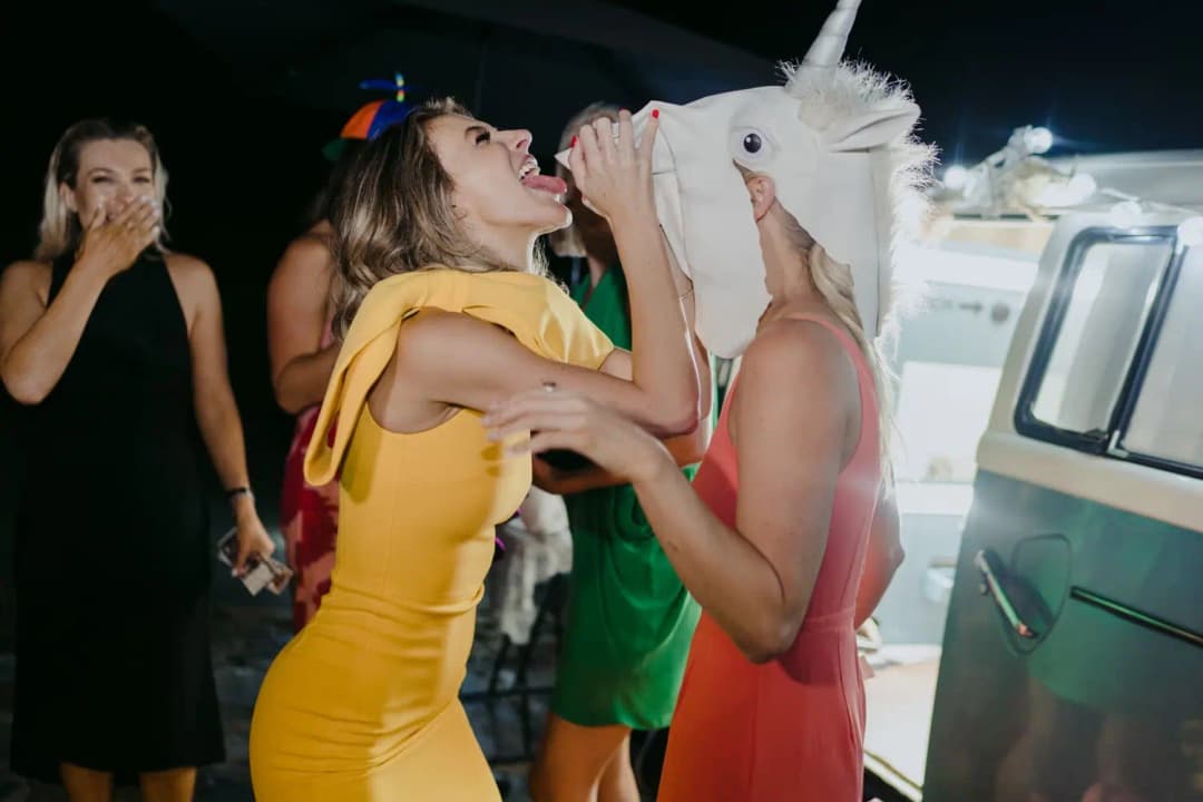 Guests wearing colourful party outfits and a horse mask at the nighttime reception.