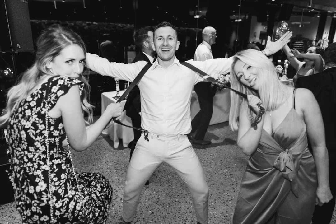 Black and white photograph of guests dancing with their arms raised.