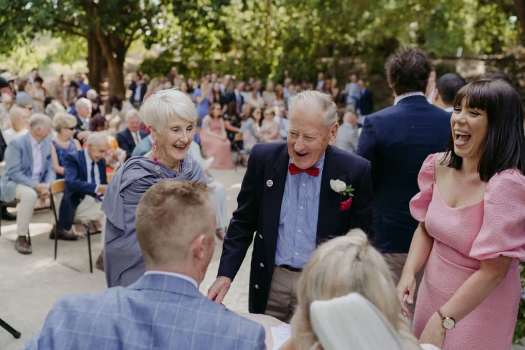 Older guests laugh as they greet people at the garden wedding.
