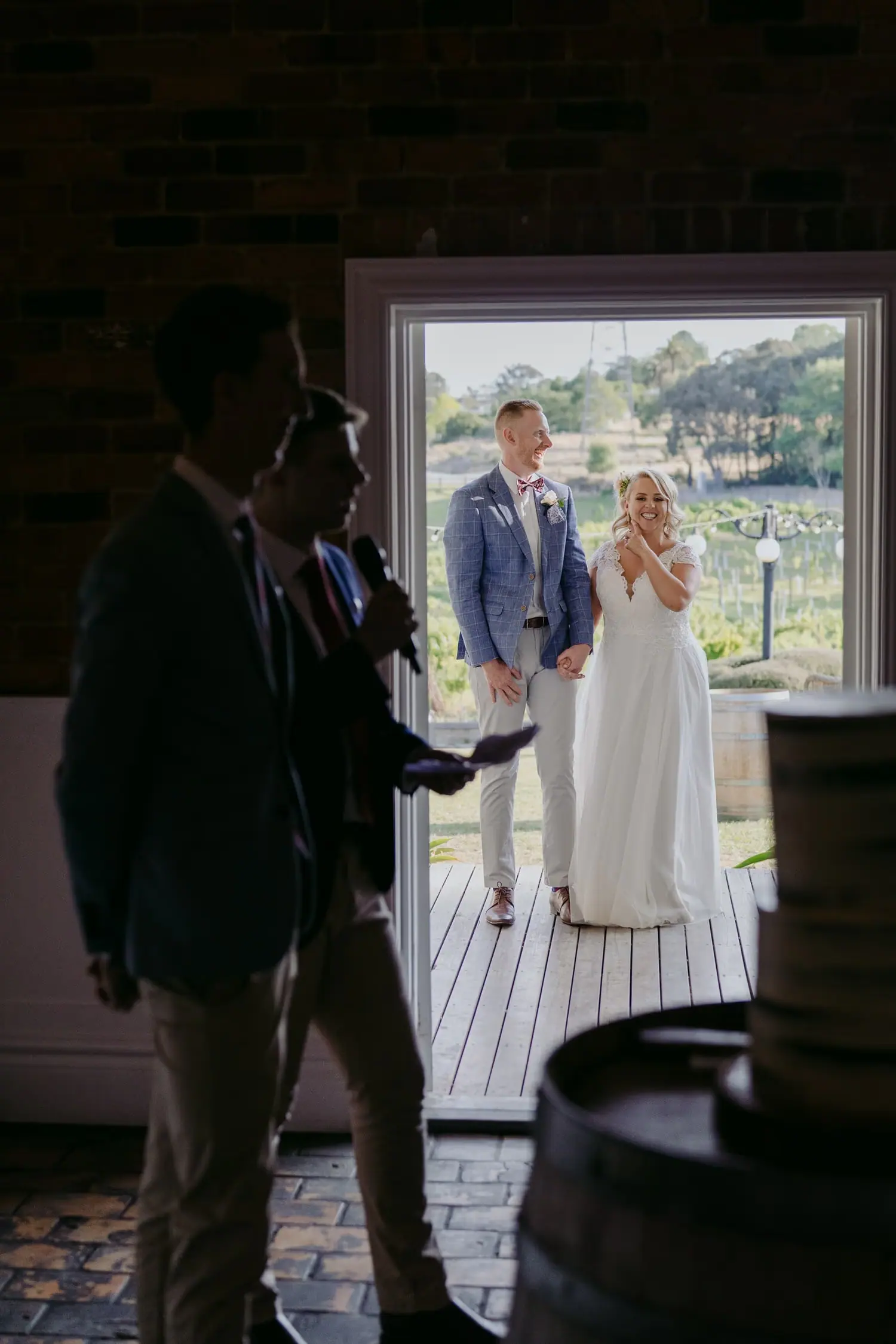 Man stands inside a dark venue with the couple visible in the bright open doorway.