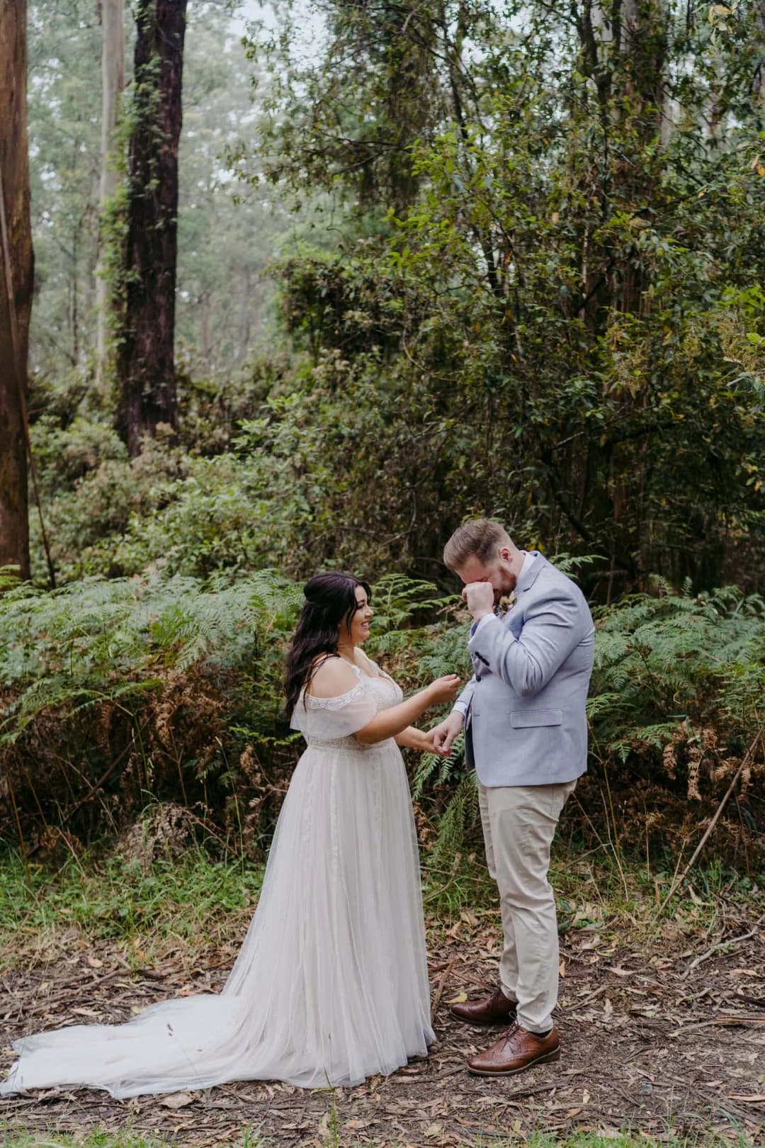 Couple faces each other beside a wooded creek at their ceremony.