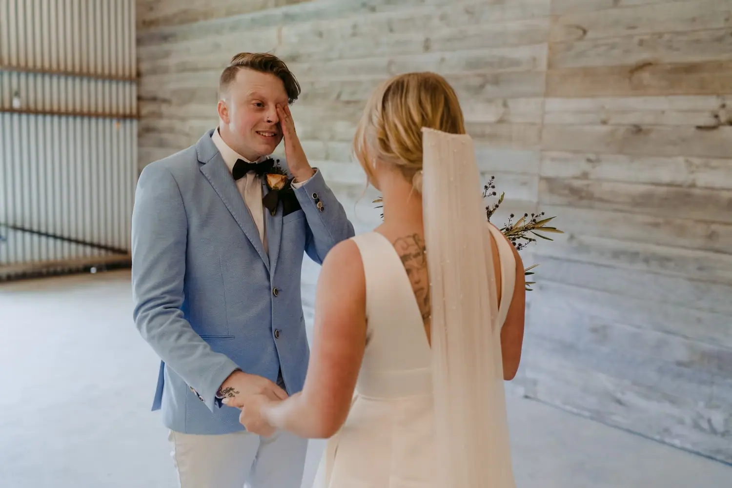 Groom wipes his eye while facing the bride during an indoor first look.
