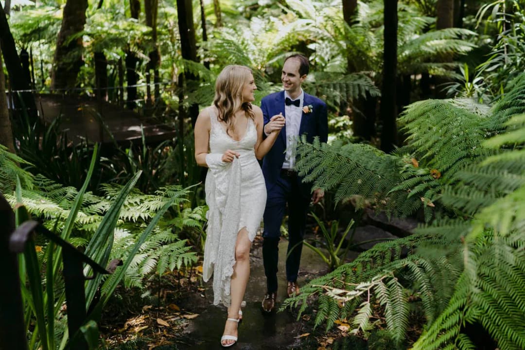 Couple walks together along a garden path surrounded by ferns.