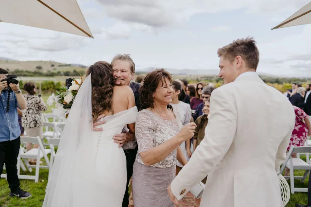 Bride and groom greeting guests beside the outdoor ceremony lawn.