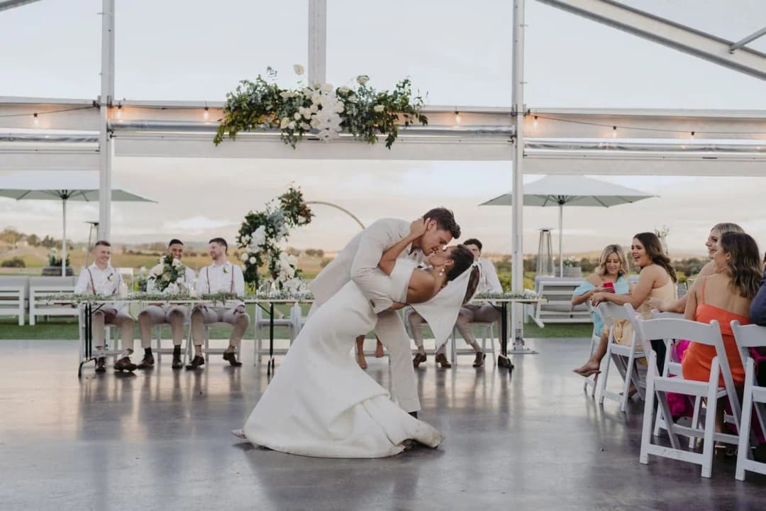 Groom dipping and kissing the bride on the marquee dance floor.