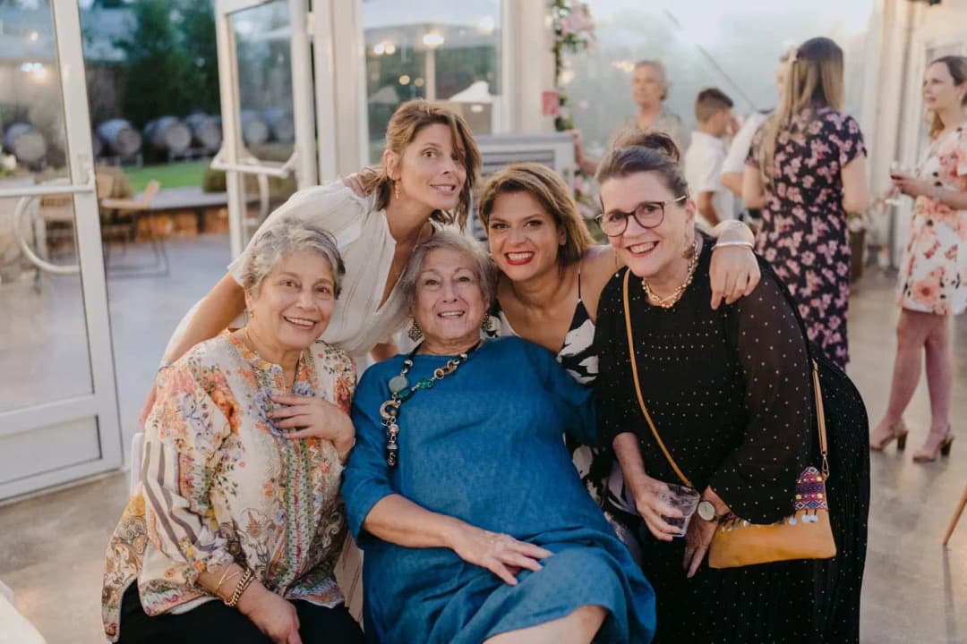 Five women smiling together inside the reception marquee.