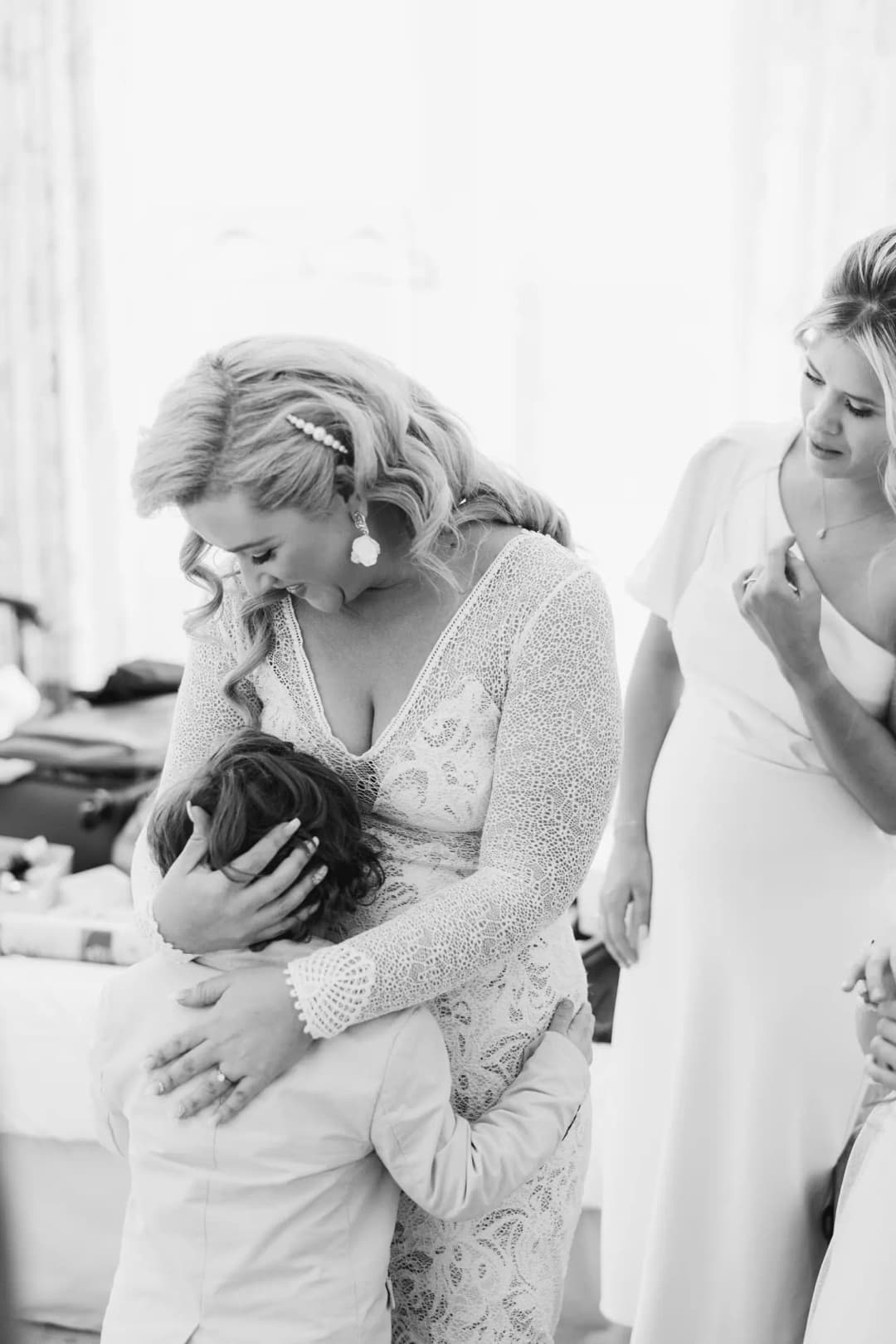 Black-and-white photograph of a small child hugging the bride's waist.