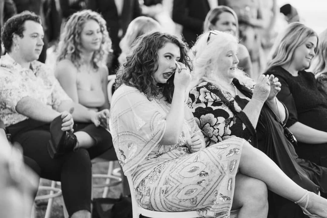 Black-and-white photograph of seated women smiling and watching the ceremony.