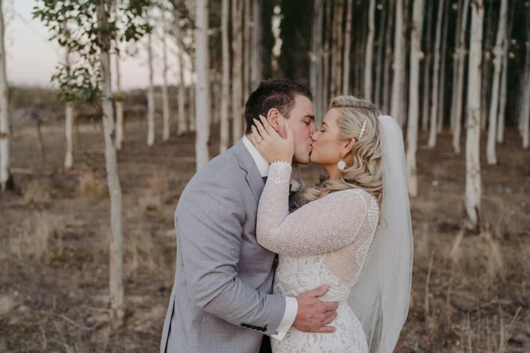 Close-up of the couple kissing in a grove of trees.