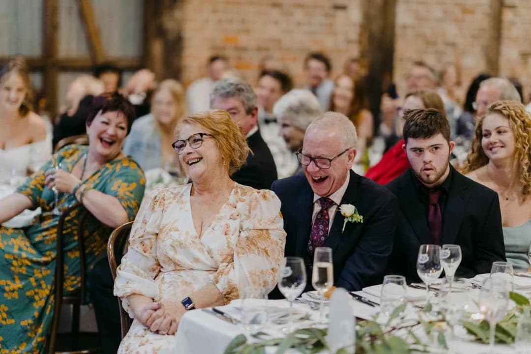 Guests laughing together at a reception table inside the rustic shed.