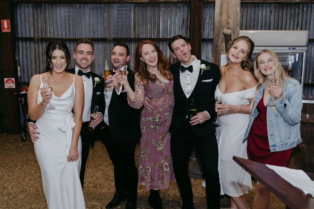 Seven guests posing together with drinks at the evening reception.