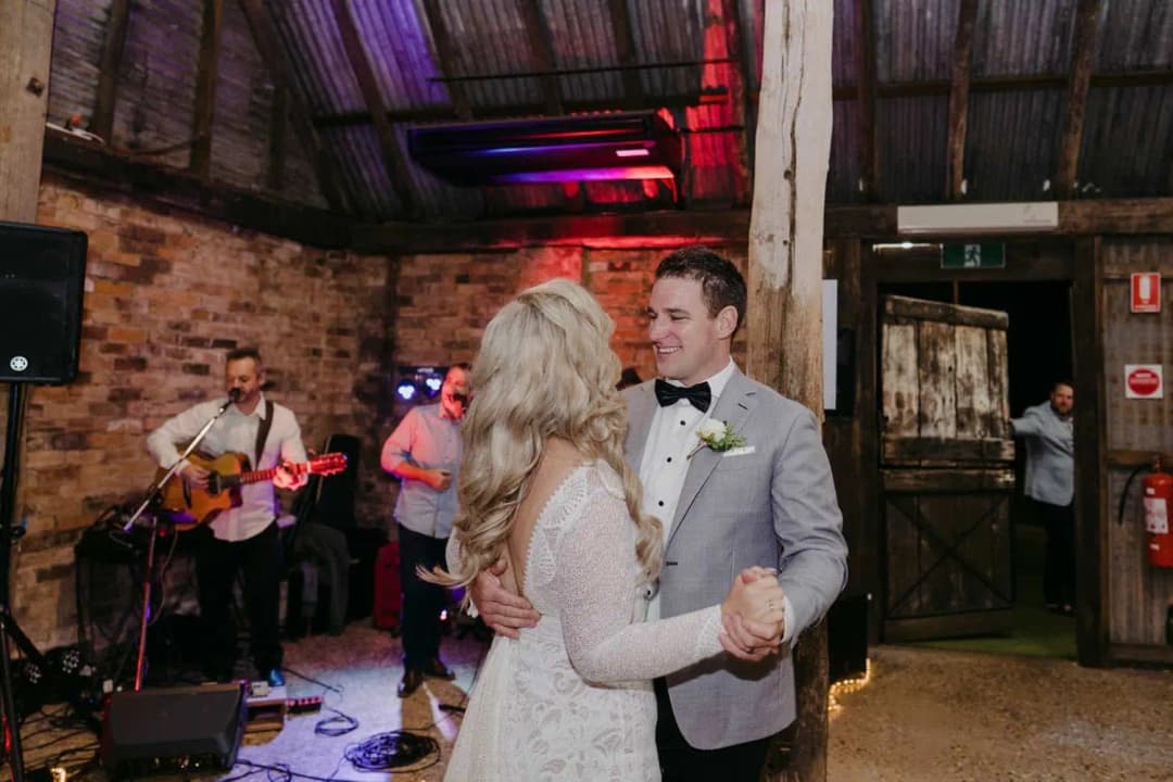 Bride and groom dancing beside a live band in the rustic reception room.