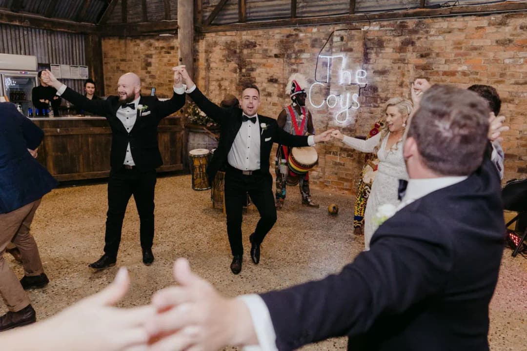 Guests joining hands and dancing in a circle with the couple.