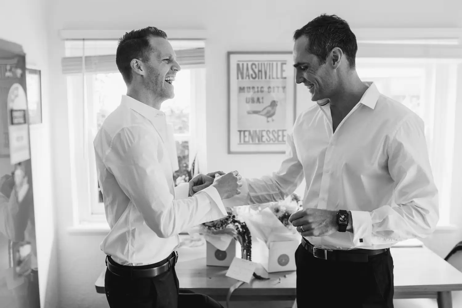 Black and white photograph of two men laughing together in white shirts