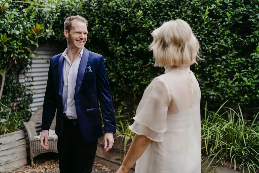 Groom smiling at the bride in a leafy backyard