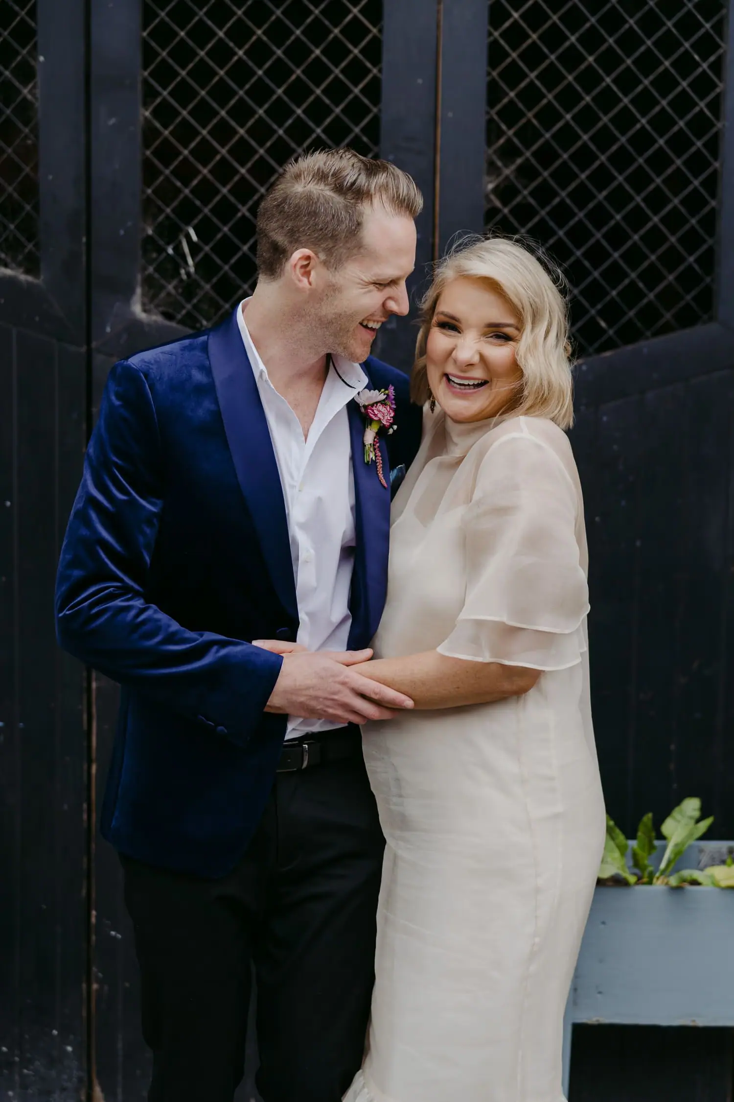 Bride and groom embracing beside a dark arched doorway
