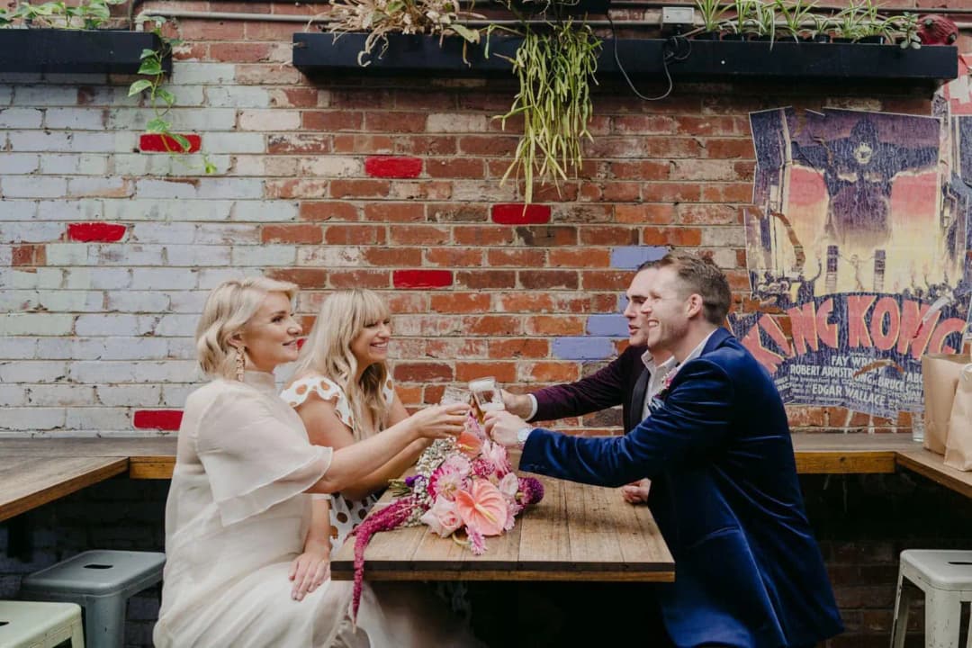 Wedding party raising glasses together around a courtyard table
