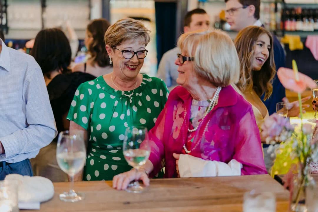 Two guests chatting with drinks beside the venue bar