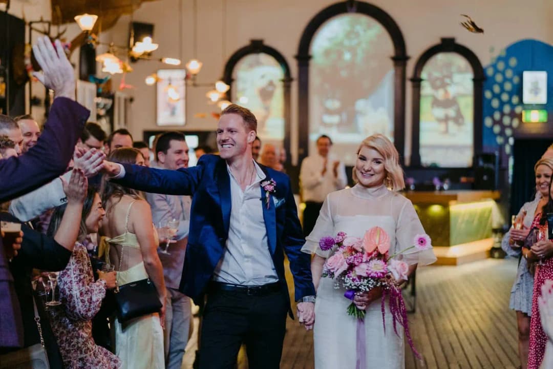 Bride and groom smiling while greeting guests along the indoor aisle