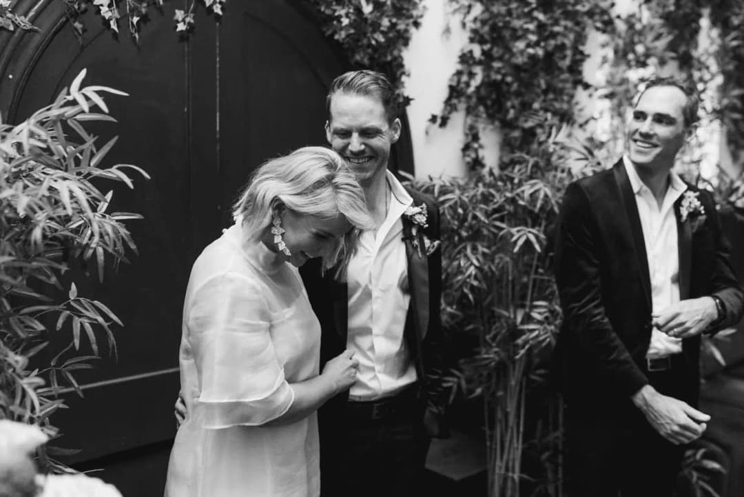 Black and white photograph of the bride laughing beside the groom and groomsman