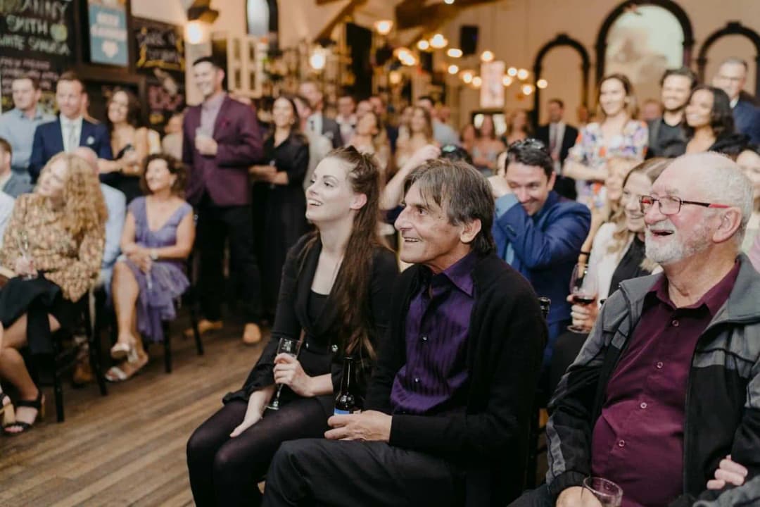 Seated guests laughing during the indoor wedding ceremony