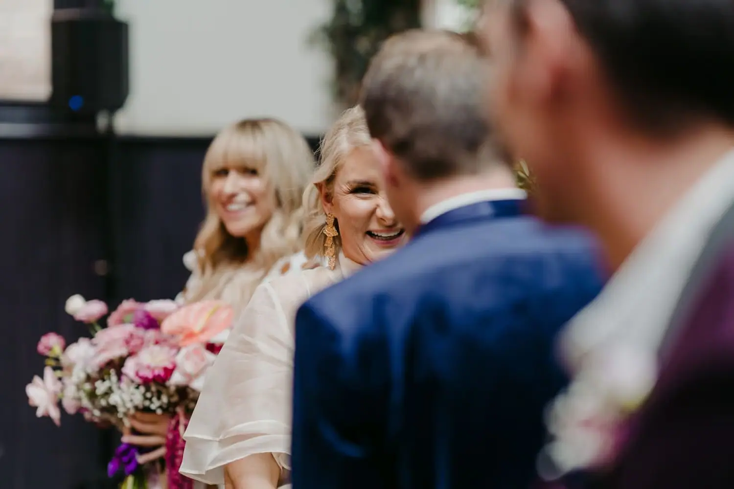 Bride smiling toward the groom as a bridesmaid stands behind her