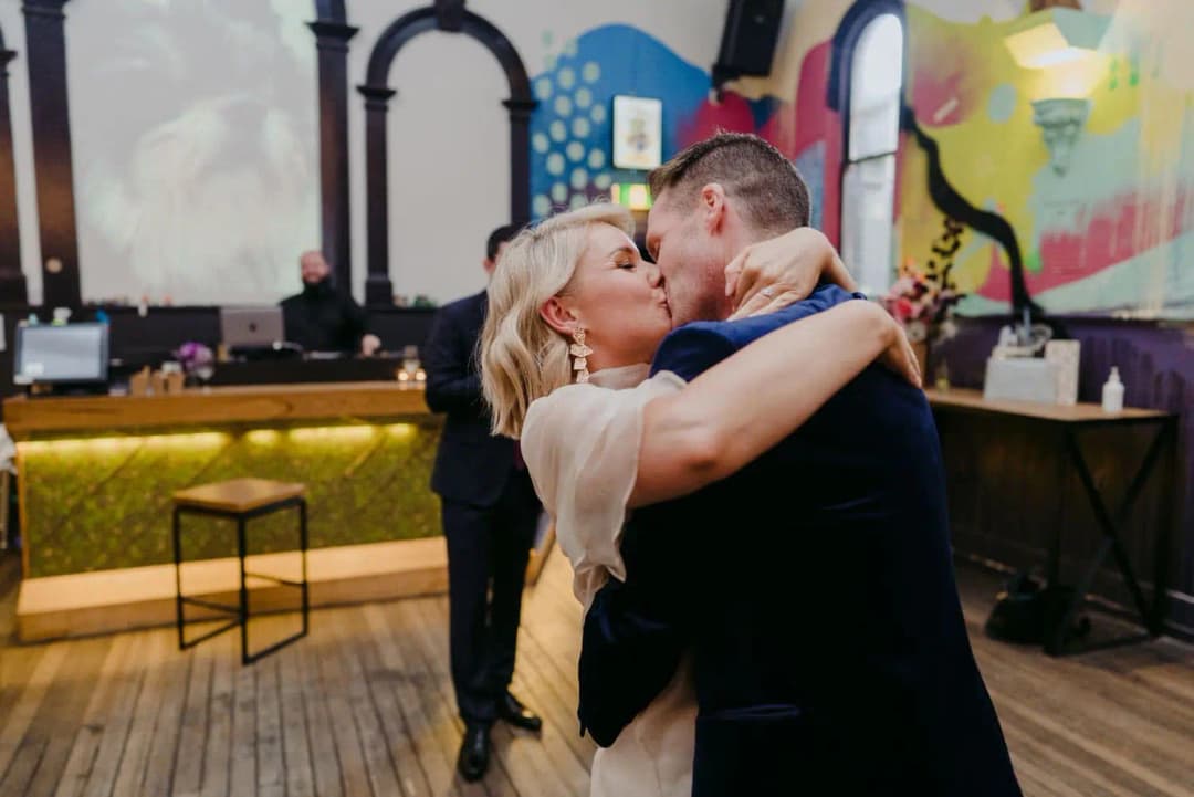 Bride and groom kissing beside the reception bar