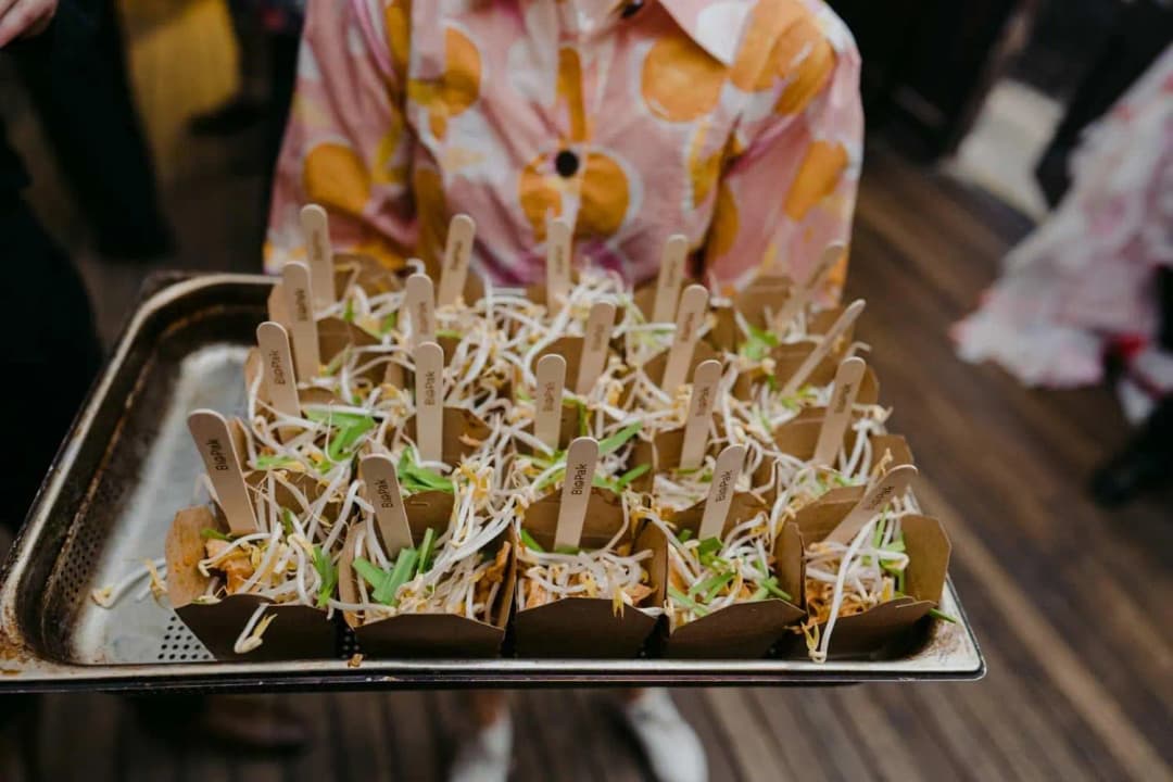 Tray of small appetisers served in individual paper boxes with wooden forks