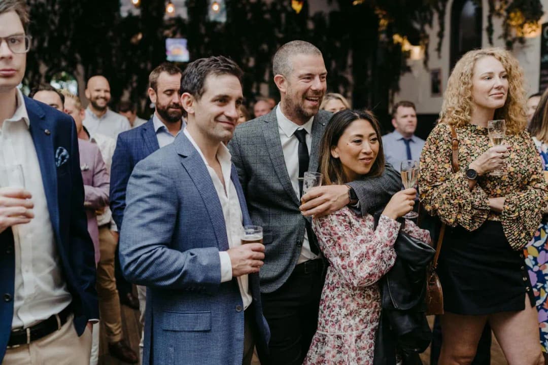 Wedding guests smiling together while holding drinks during the reception
