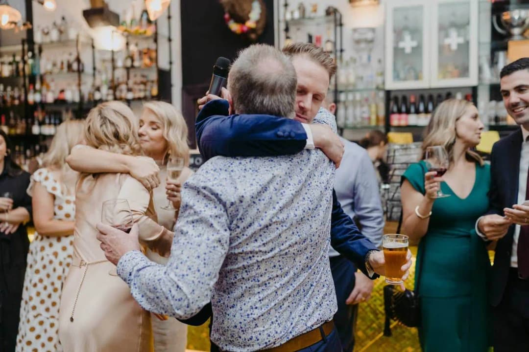 Wedding guests embracing each other beside the bar