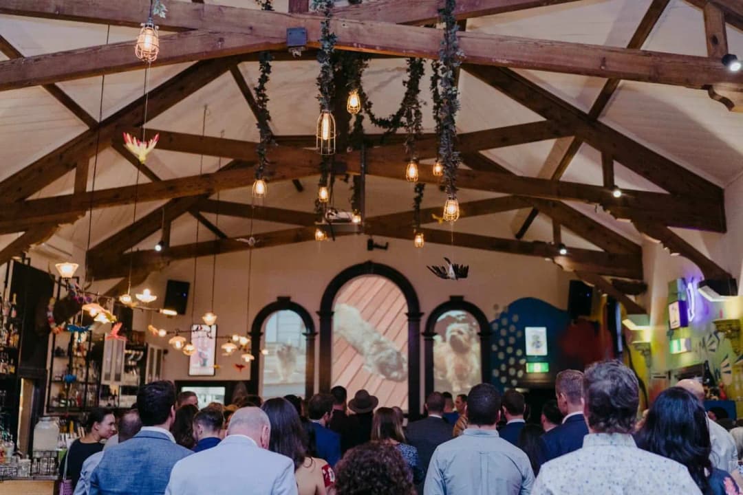 Wide view of guests facing the front of the reception beneath exposed timber beams