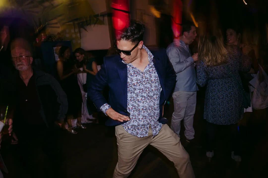 Guest in sunglasses dancing beside other reception guests