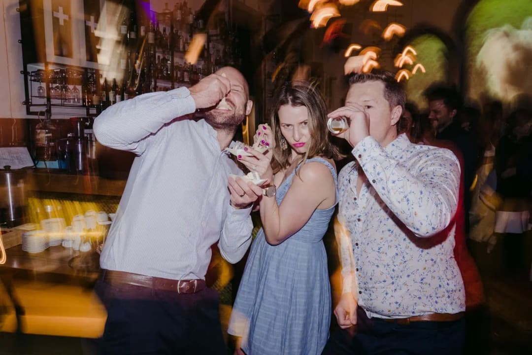 Three guests posing with drinks on the dance floor