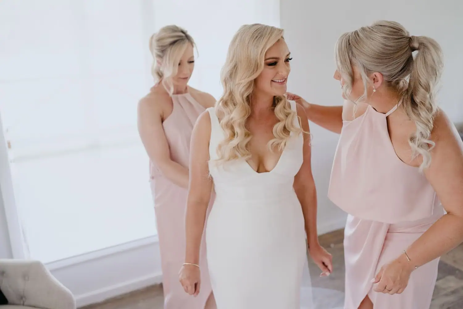 Bride smiling beside two bridesmaids in pink dresses